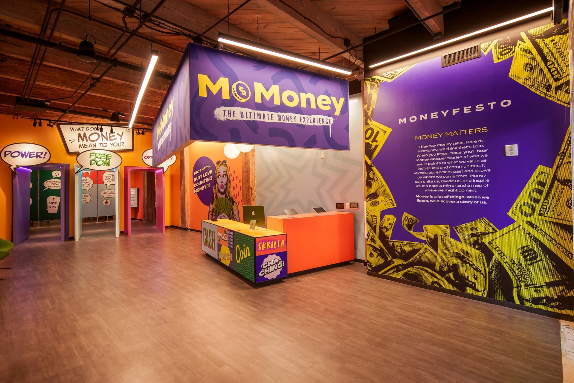MoMoney's lobby: purple signage above an orange reception desk, with speech-bubble doorways and the Moneyfesto wall.