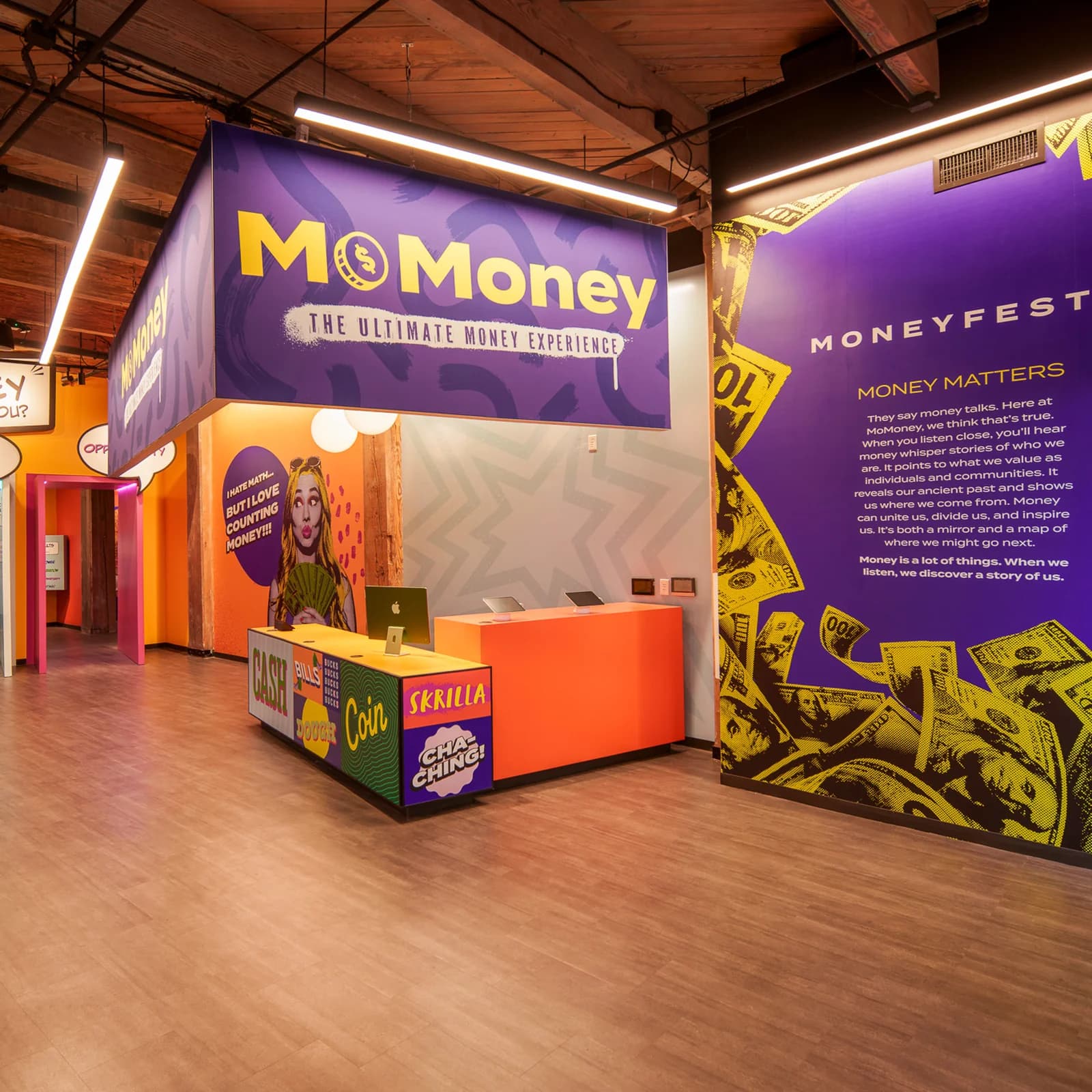MoMoney's lobby: purple signage above an orange reception desk, with speech-bubble doorways and the Moneyfesto wall.