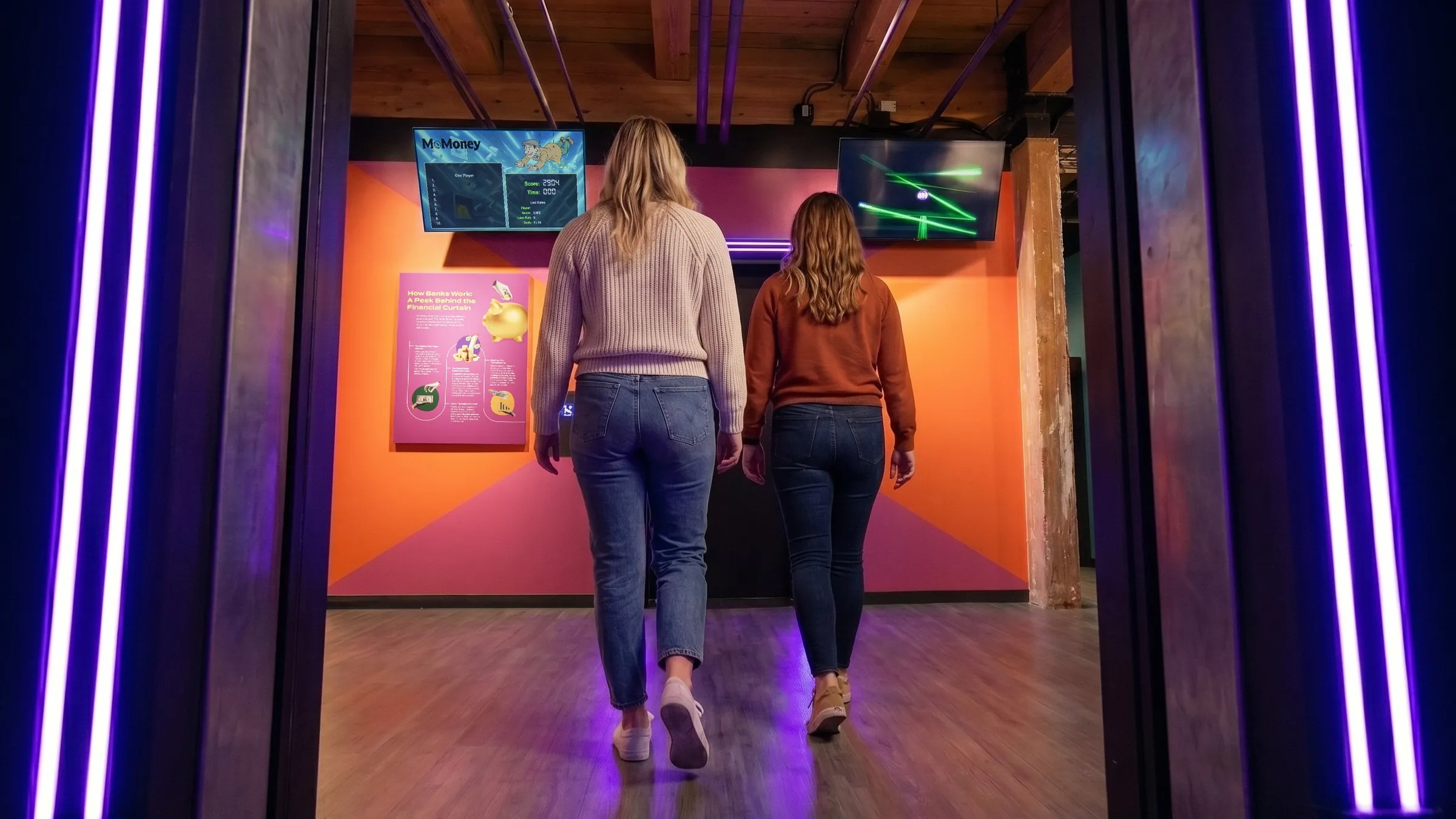 Two visitors walking into MoMoney's heist exhibit, one of 28 interactive money experiences inside.